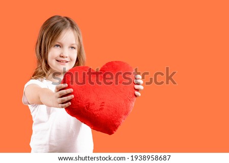 Love sign. Beautiful girl gives a big red toy heart