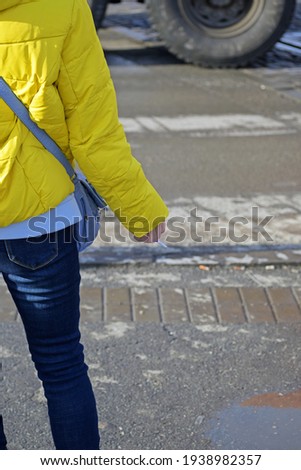 A woman with a cigarette in her hand waits for the traffic light to clear