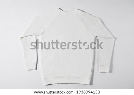 Classic jacket lying on a light background. White jacket without inscriptions and logos in a white studio. New collection of stuff for people. Concept of simplicity and style of garment