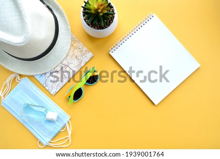 Travel kit (hat, map, antibacterial Gel, medical mask,monopod, passport) on a yellow background. Travel flat lay