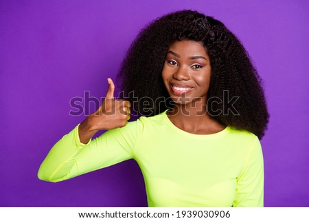 Photo of young pretty cheerful smiling afro girl showing thumb up advertisement isolated on purple color background