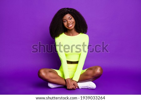 Full size photo of young beautiful charming smiling afro sportive woman sit floor relaxing isolated on purple color background