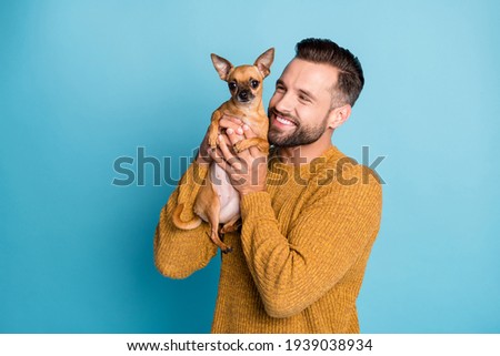 Photo of young happy positive smiling handsome man holding doggy chiahuahua isolated on blue color background
