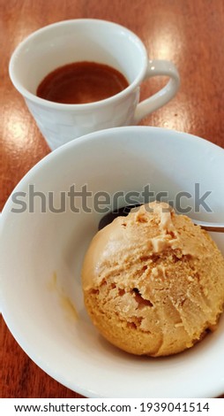 Affogato coffee concept, close up salted caramel iced cream in white cup with espresso shot in small mug, vertical picture cool beverage on wooden table, sweet and caffeine in afternoon break