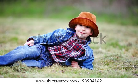 Happy smiling boy dressed in country style playing in the park near sunset with shallow depth of field and copy space to left and right 