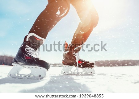 Legs in skates freely skate on the ice of the lake in nature against the backdrop of a landscape