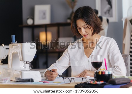 Woman sitting at tailor workshop and sketching