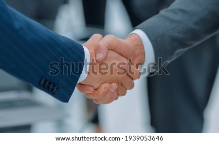 Two businessmen shaking hands with colleagues on background. Royalty-Free Stock Photo #1939053646