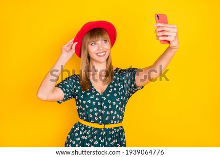 Portrait of charming cheerful girl taking selfie posing touching hat having fun isolated over bright yellow color background