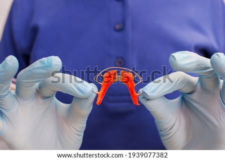 Dentistry concept. Removable orthodontic appliance, orthodontic plate of colored plastic.Background. orthodontist dentist holds a children dental plate in his hands. Copy space. Bite correction. Royalty-Free Stock Photo #1939077382