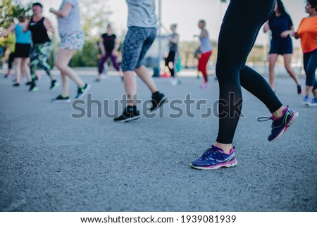 Photo of legs in sportswear and shoes dancing zumba during the class outside on the street