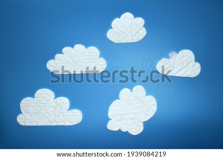cardboard clouds on a blue plastic background in cartoon style