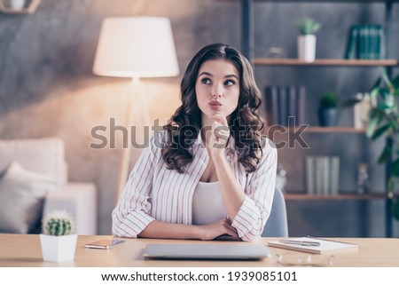 Photo of charming sweet young lady wear white shirt thinking hand arm chin sitting table indoors inside room home
