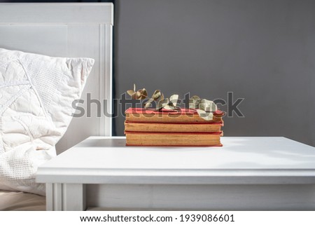 books on retro white table by bed    Scandinavian interior  neutral color palette.