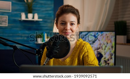Woman blogger sitting in home studio looking at camera preapring for live recording podcast show. On-air online production internet broadcast host streaming web content record digital blog