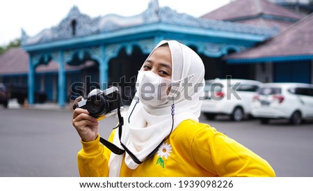 Asian woman traveler in keraton solo wearing yellow clothes and hat with vintage analog camera
