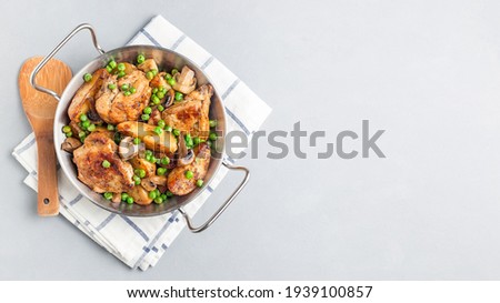 Chicken with potatoes, mushrooms and green peas, in a metal pot, horizontal, top view, copy space