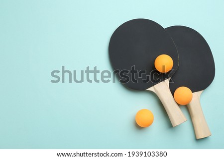 Ping pong rackets and balls on turquoise background, flat lay. Space for text