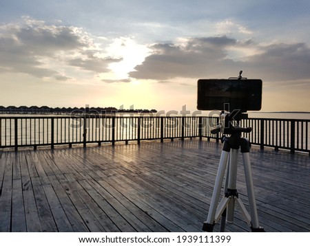 Handphone set up on tripod to capture time lapse video of beautiful sunset view in Bagan Lalang beach, Selangor, Malaysia. 