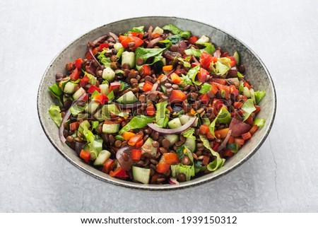 salad with lentils and vegetables in a deep plate on a gray background, vegetarian food Royalty-Free Stock Photo #1939150312