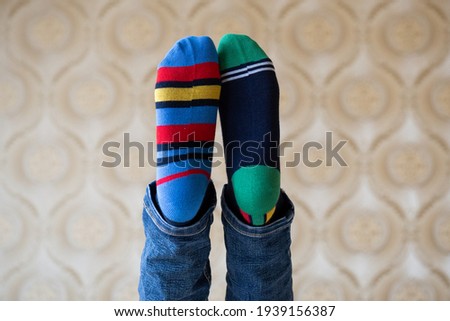 Legs in bright funny different socks are raised up. March 21, world down syndrome day Royalty-Free Stock Photo #1939156387