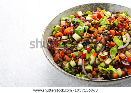 salad with lentils and vegetables in a deep plate on a gray background, vegetarian food Royalty-Free Stock Photo #1939156963