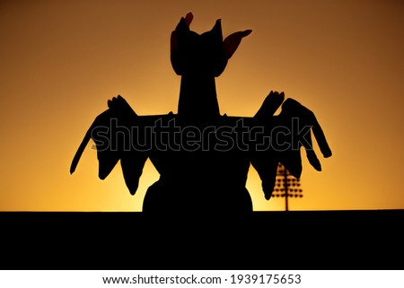 A picture of a man wearing a dragon mascot standing in the sun.