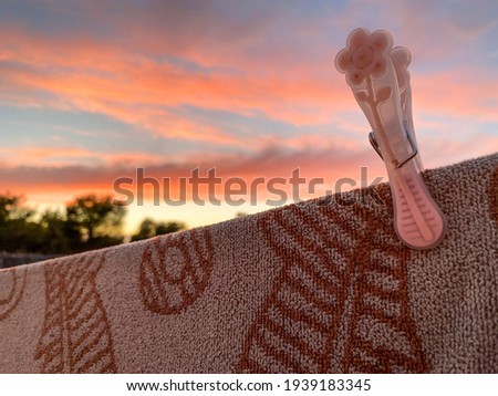 Close-up plastic pecs clipped to a clothes hanging rope outside in open air, with nature background and sunset