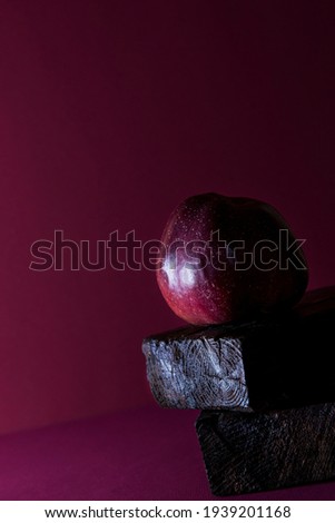 a red apple on a maroon background with space for text is a concept of simplicity and elegance. the effect of moving at an angle. Geometry.advertising innovations of exclusive products. company brand
