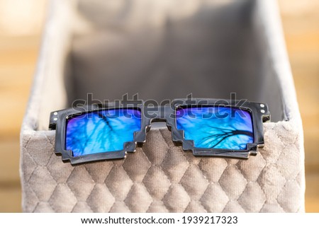Black pixel sunglasses with blue lenses closeup in a sunny day. Selective focus