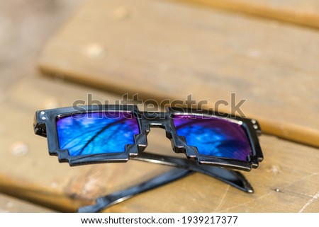 Black pixel sunglasses with blue lenses closeup in a sunny day. Selective focus
