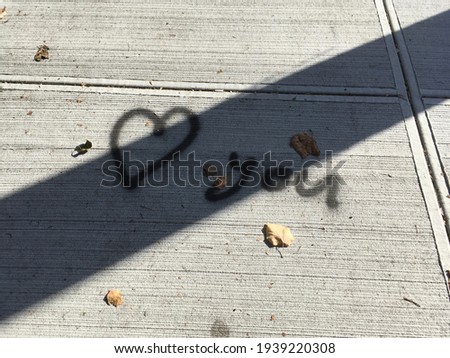 on the road it is written i love you and is crossed out by the shadow of a pillar