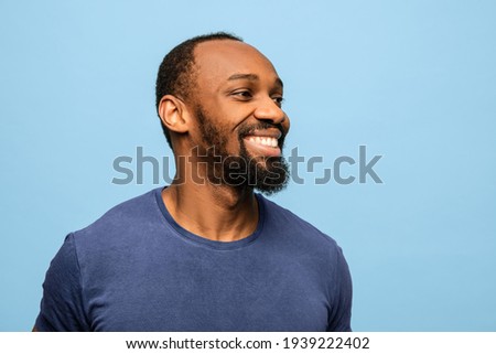 Half-length portrait of smiling joyful African-American man in casual clothes isolated over blue background. Concept of human emotions, facial expressions, funny, happiness. Copy space for ad.