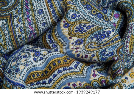 top view closeup on crumpled soft cotton scarf with bright oriental and paisley ornament with blue, pink, and yellow colors