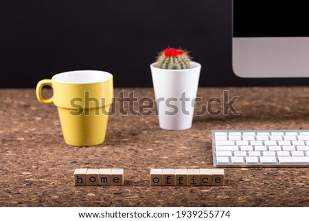 Close up view of a black work desk interior with a laptop computer, a cup of coffee,  paper, pen and, cactus with flowers black background