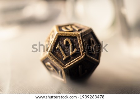 High contrast close-up image of a 12-sided role playing die surrounded by smoke.