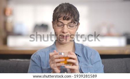 Young woman drinking herbal tea in her peaceful home. Young woman with glasses is drinking herbal ,black tea. 