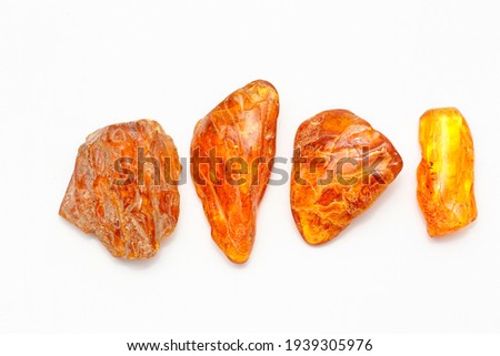 Four different transparent polished yellow amber pieces on a white background. Sun stone. Natural mineral material for jewelry. Amber texture. Copal. Multicolored yellow background. Ancient  resin Royalty-Free Stock Photo #1939305976