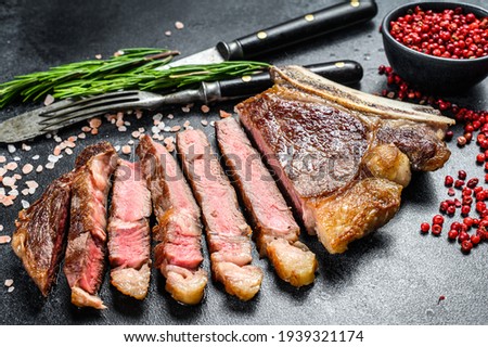 Grilled cowboy or ribeye beef steak with herbs and spices. Black background. Top view