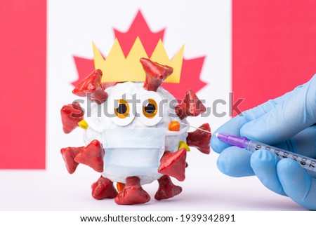 Vaccination against Covid-19 in Canada. Hand in medical glove making injection to a cartoon Covid-19 model in a protective medical mask in front of flag of Canada.
