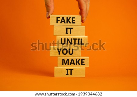 Fake it until you make it symbol. Wooden blocks with words 'Fake it until you make it'. Businessman hand. Beautiful orange background. Business, popular quotation concept. Copy space.