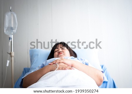 Blurred soft images of Asian fat woman patients, lying in patient's bed with alone, to people health care and diabetes concept. This picture focused on hands