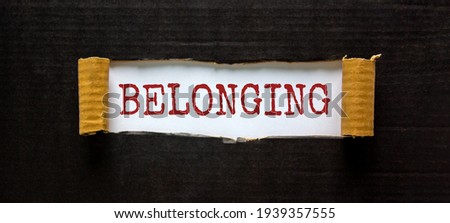 Belonging and inclusion symbol. The word 'belonging' appearing behind torn black paper. Beautiful black background. Business, inclusion and belonging concept. Copy space.