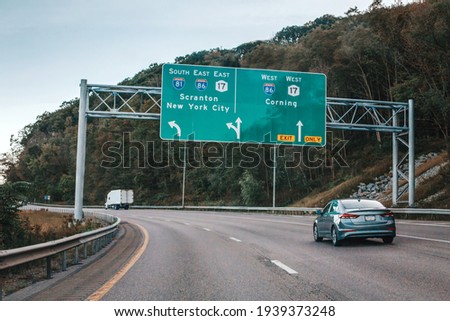 Cars on highway in American USA city country. Road to New York city. Green blue street signs to NY city. Empty road highway on summer day outdoors. Street road signs.
