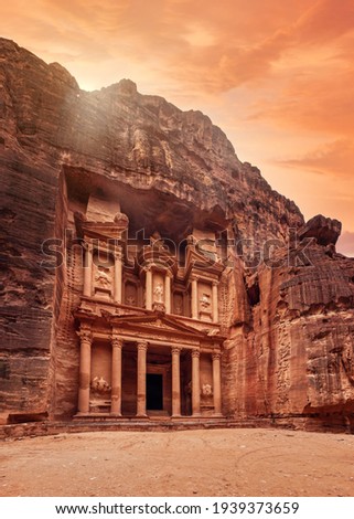 Front of Al-Khazneh (Treasury temple carved in stone wall - main attraction) in Lost city of Petra, orange sunset sky above Royalty-Free Stock Photo #1939373659