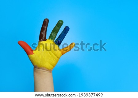 Child hand painted in colorful paint on a blue background