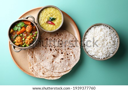 vegetarian Indian thali or Indian home food with lentil dal, cauliflower curry, roti or Indian flat bread and rice Royalty-Free Stock Photo #1939377760