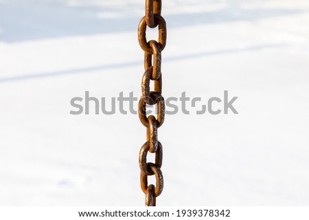 A worn iron chain on a white snow background.