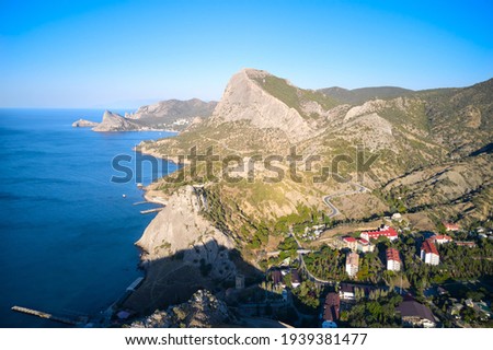 The rocky coast of the sea with a settlement and a mountain road. Shooting from a drone.