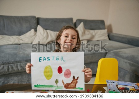 A happy little girl showing her beautiful drawing to the camera, Easter theme